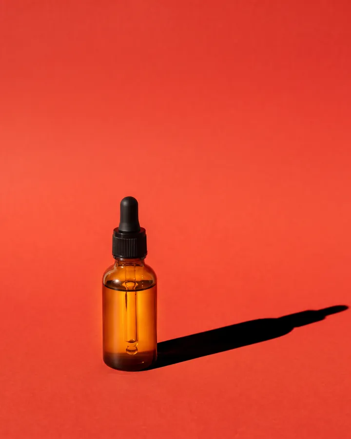 The bottle on a tomato-red backdrop.