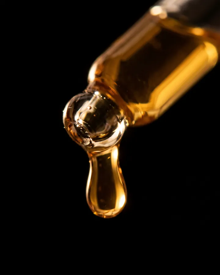 A golden drop at the tip of a dropper.